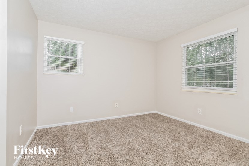 a bedroom with carpet and two windows