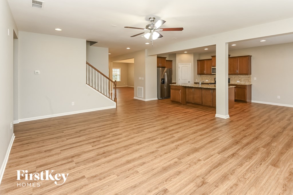 A spacious room with wooden floors and a ceiling fan.