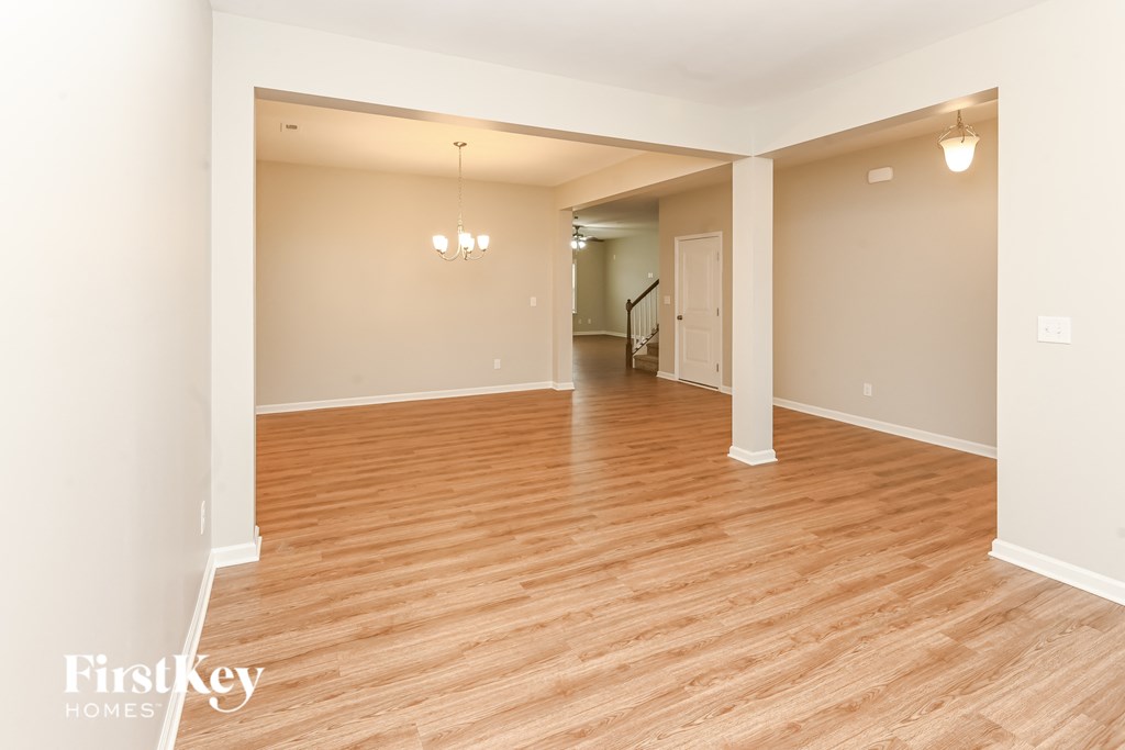 A spacious room with wooden flooring and a chandelier.