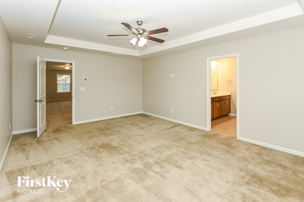 A spacious room with a ceiling fan and carpeted floor.