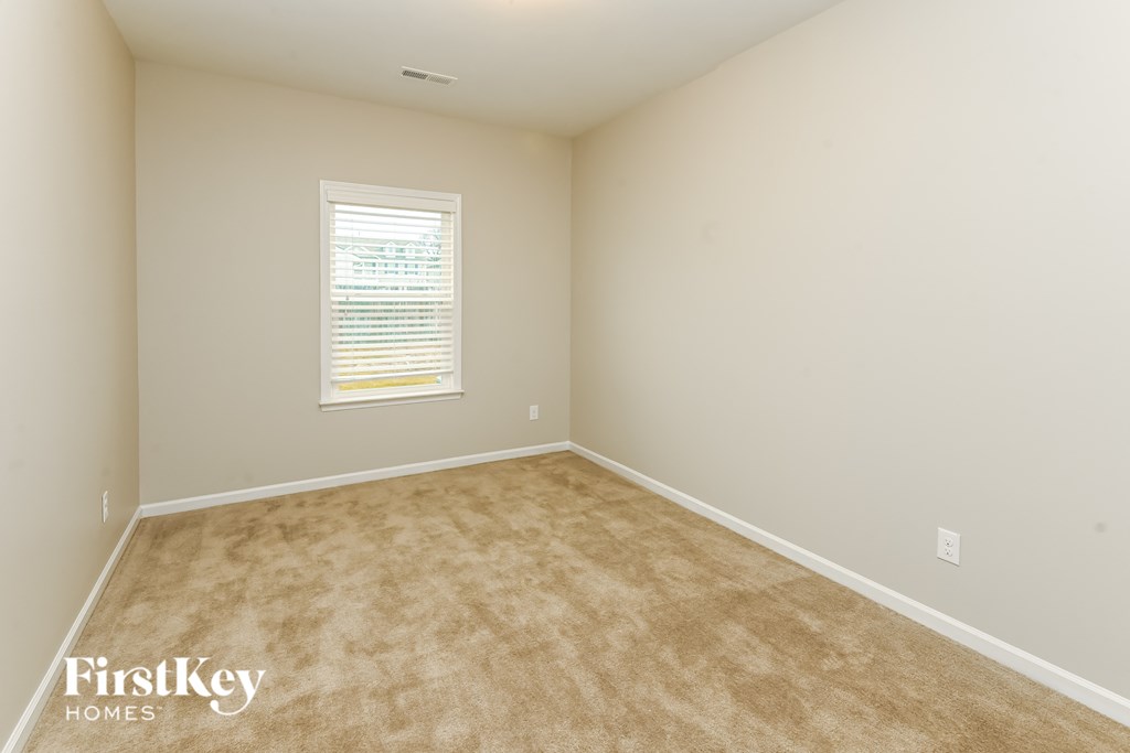 A room with a window and carpeted floor.