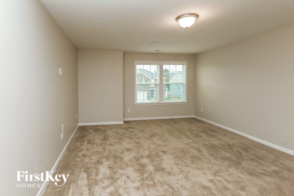 A room with a carpeted floor and a window with blinds.