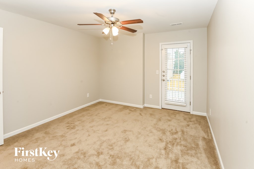 A room with a ceiling fan and a door with a window.
