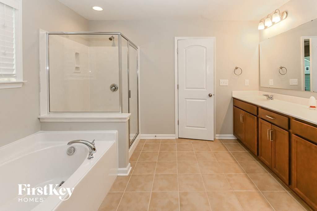 A bathroom with a white tub and wooden cabinets.