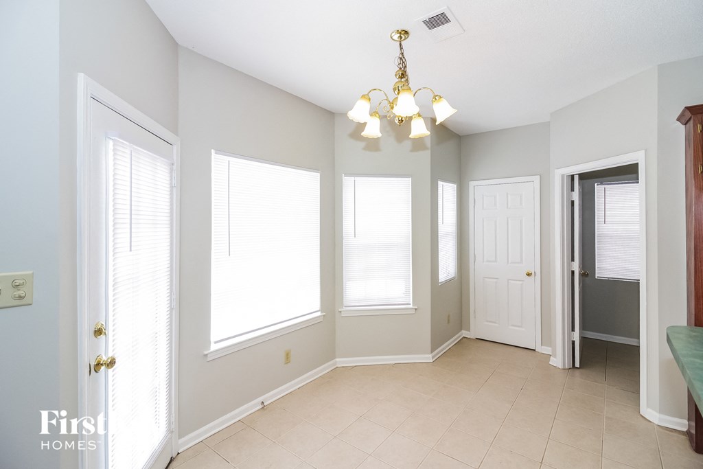 A well lit room with a chandelier and a bench.