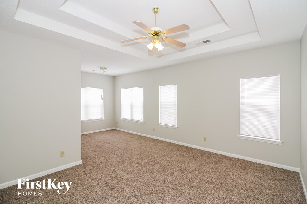 A spacious room with a carpeted floor and a ceiling fan.