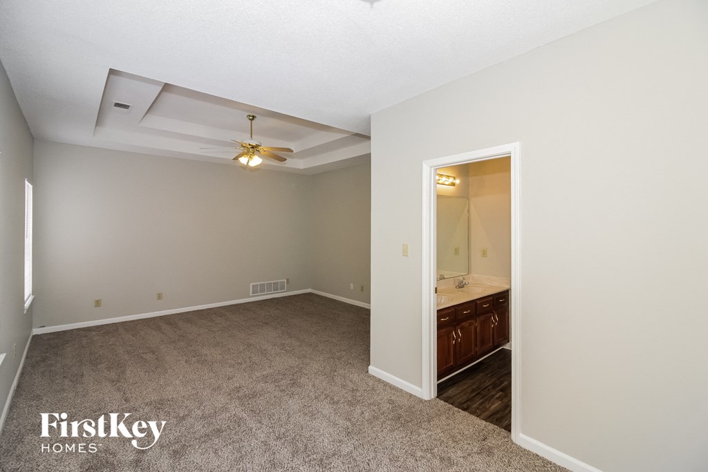 A spacious room with a carpeted floor and a ceiling fan.