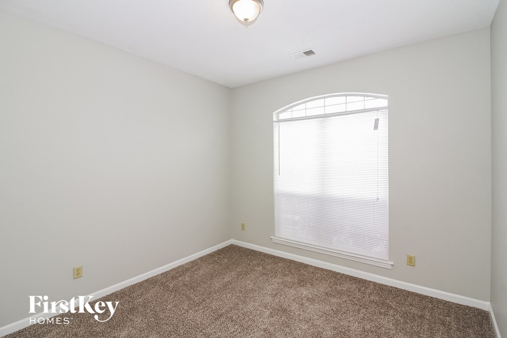 A room with a carpeted floor and a window with blinds.