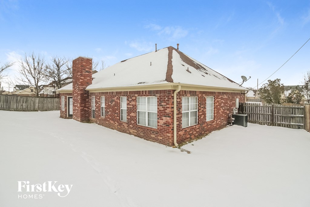A brick house with a chimney and a fence in the front yard.