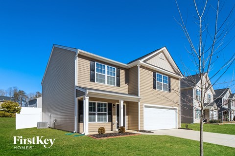 a beige house with a white garage door and a lawn
