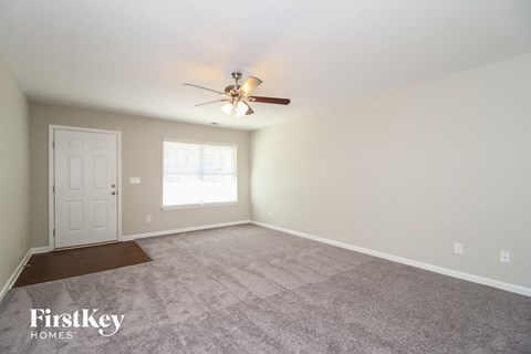 the spacious living room with carpeting and a ceiling fan