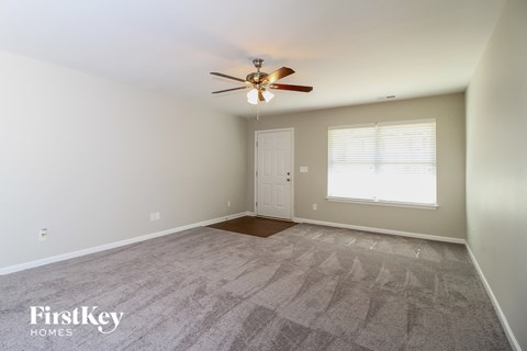 the spacious living room with carpet and ceiling fan