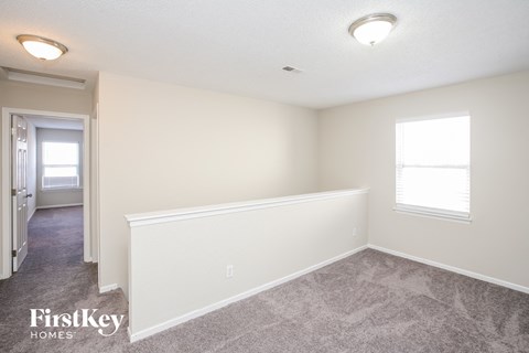 a bedroom with white walls and carpet and a door to a hallway