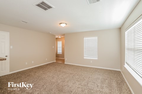 A spacious room with a carpeted floor and a doorway leading to another room.