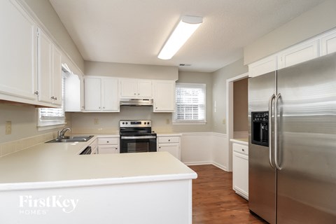 A kitchen with white cabinets and a stainless steel refrigerator.