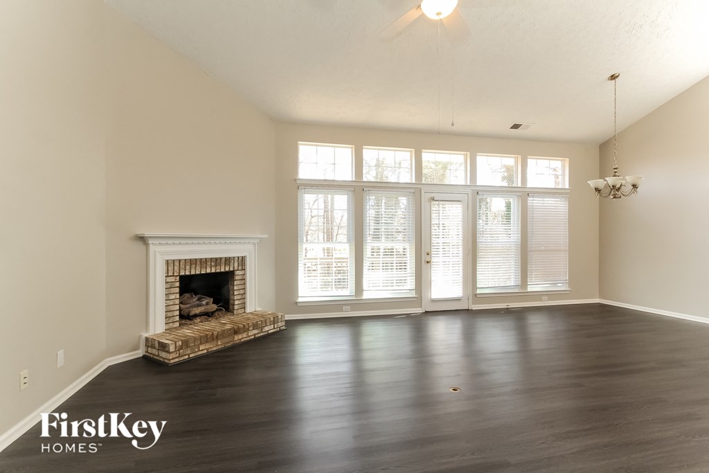 A large empty room with a fireplace and wooden floors.