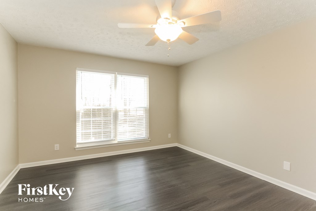 A room with a ceiling fan and a window with blinds.