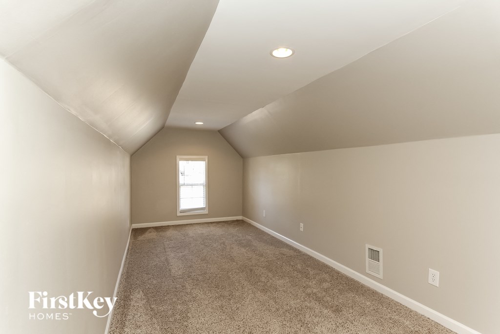 A spacious room with a carpeted floor and a window.