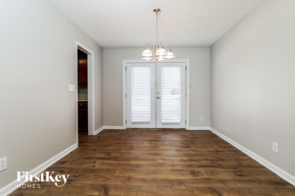 a living room with a hardwood floor and a door to a room with white
