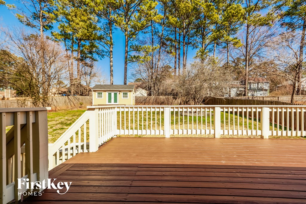 a deck with a white railing and a yard with trees