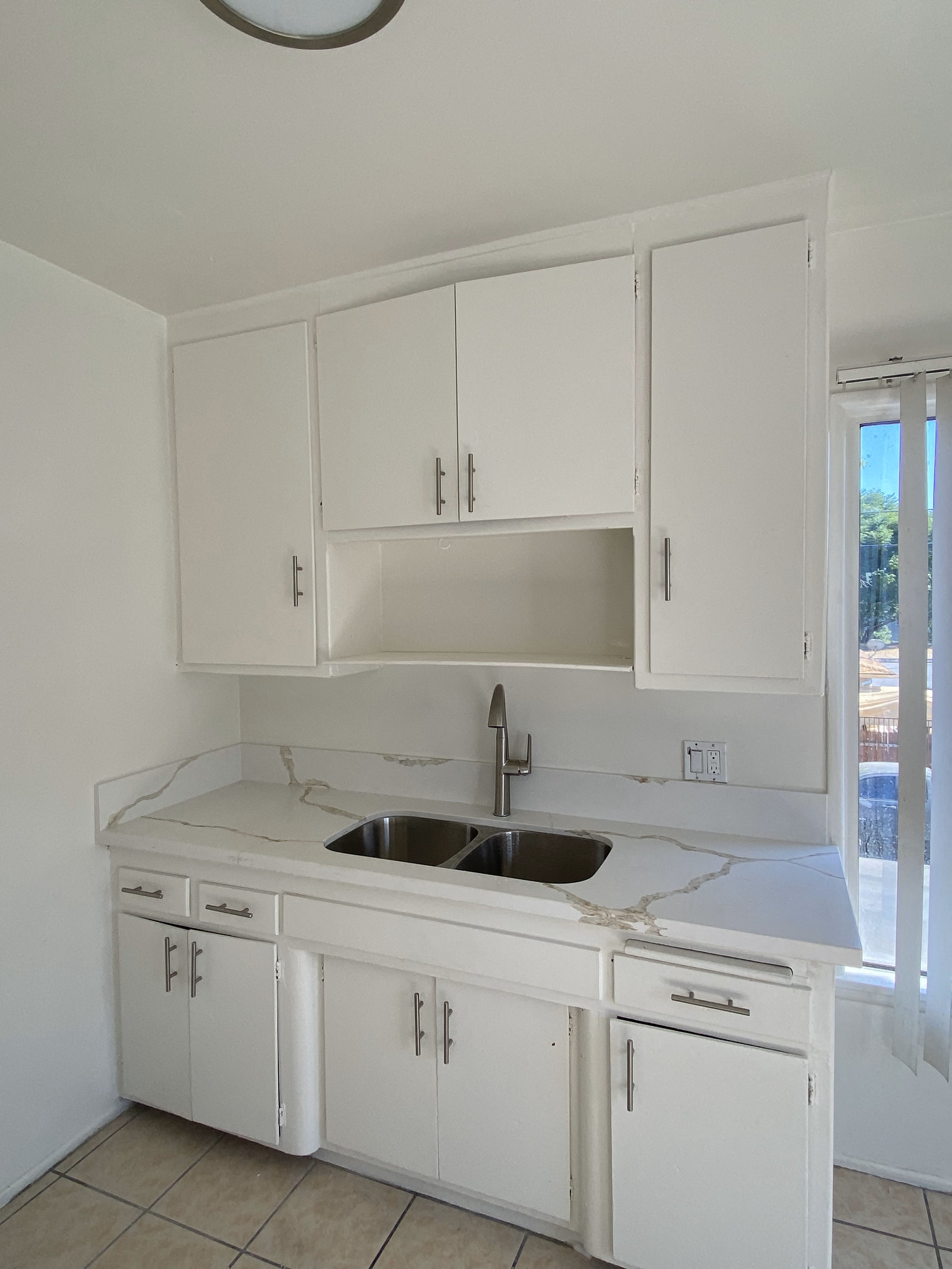 an empty kitchen with white cabinets and a sink