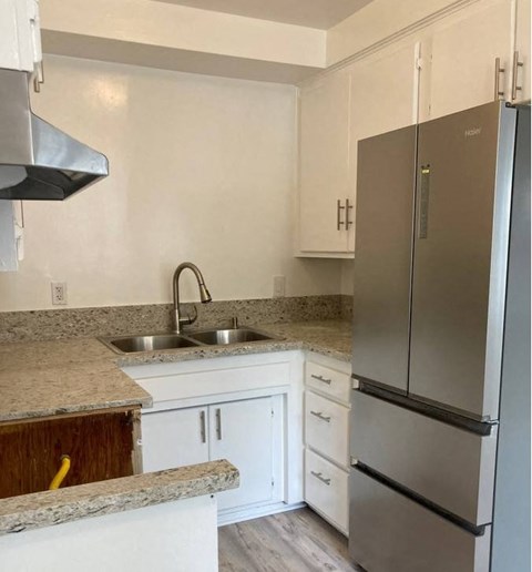 a kitchen with white cabinets and a stainless steel refrigerator