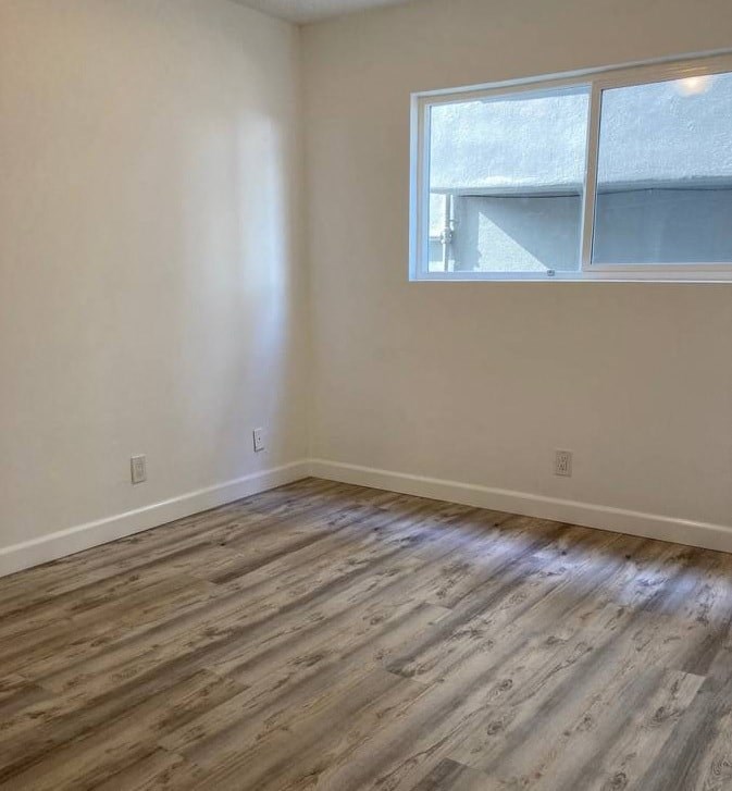 an empty room with a window and wooden floors