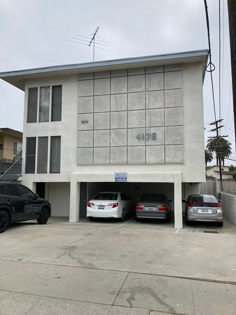 A black car is parked in front of a building with the number 4176 on it.