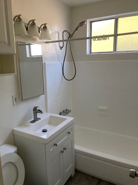 A white bathroom with a toilet, sink, and a window.