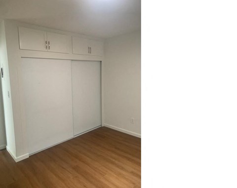 an empty bedroom with white walls and wood floors