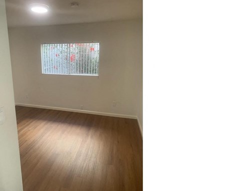 an empty living room with wood floors and a window