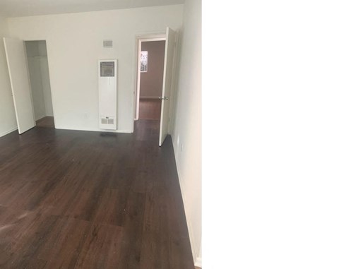 an empty living room with wood flooring and white walls