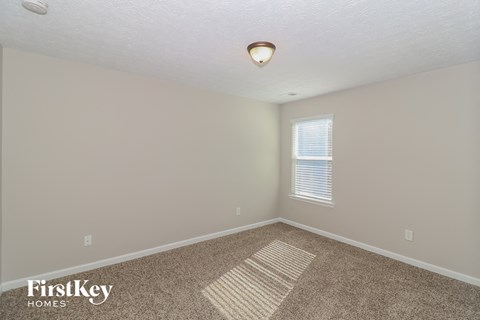 the spacious upstairs bedroom with carpeted flooring and a window