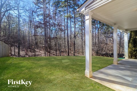 a porch with a lawn and trees in the background