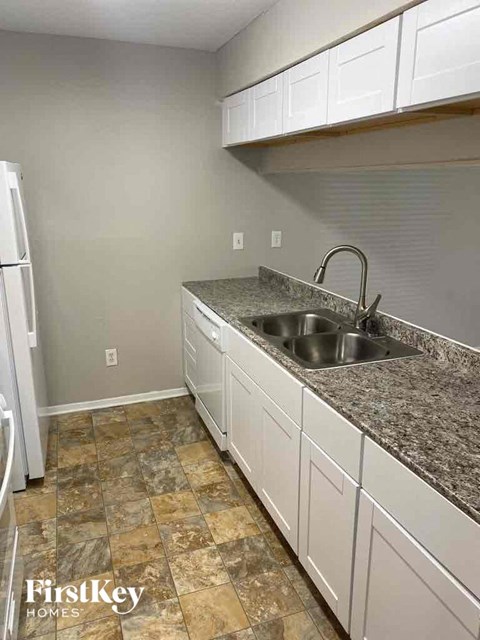 an empty kitchen with granite counter tops and white cabinets