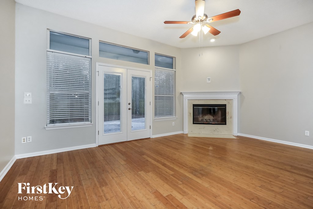 an empty living room with a fireplace and a ceiling fan