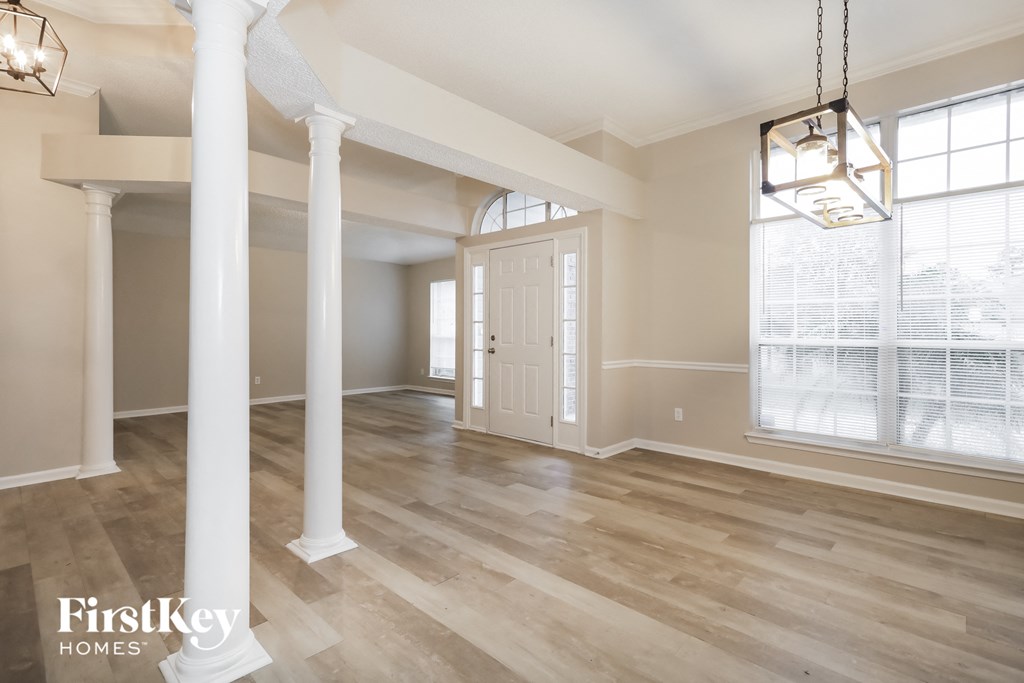 an empty living room with white pillars and a white door