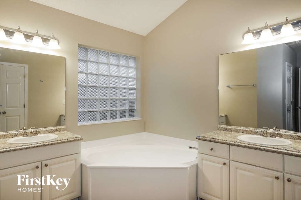 a white bathroom with two sinks and a tub