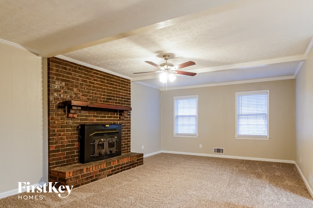 a living room with a brick fireplace and a ceiling fan