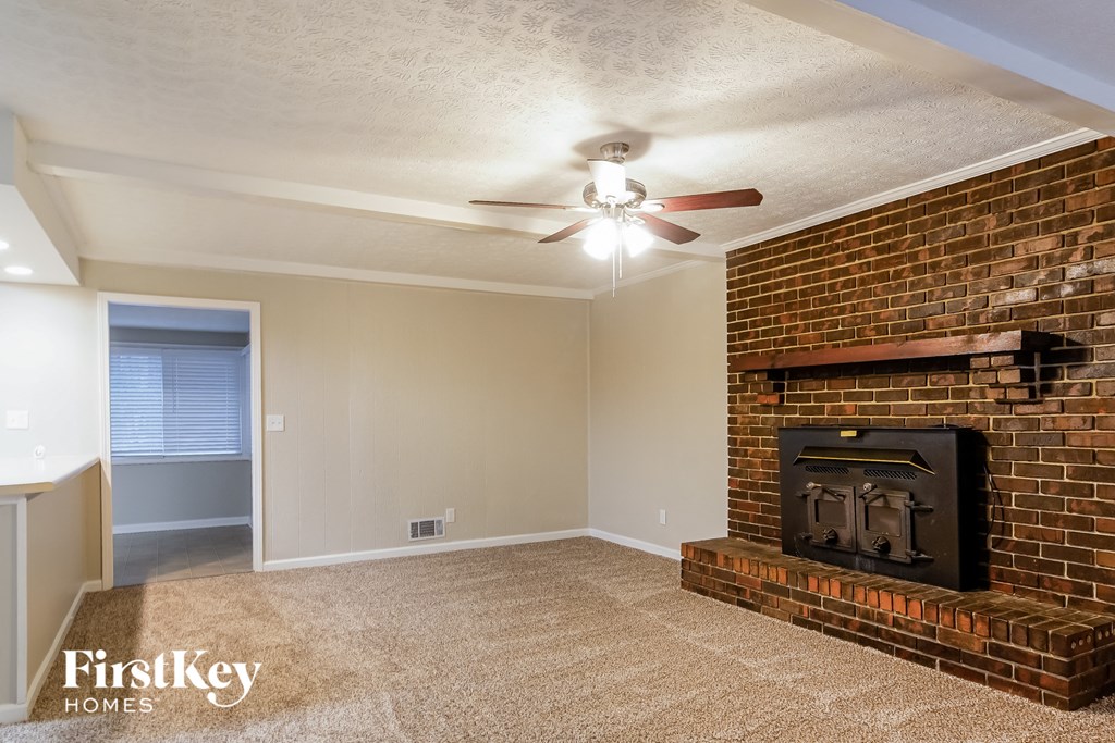 a living room with a brick fireplace and a ceiling fan