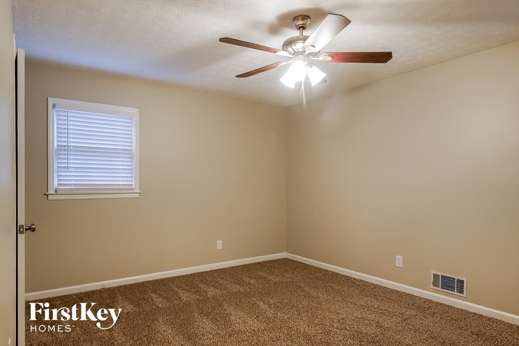 an empty room with a ceiling fan and a window