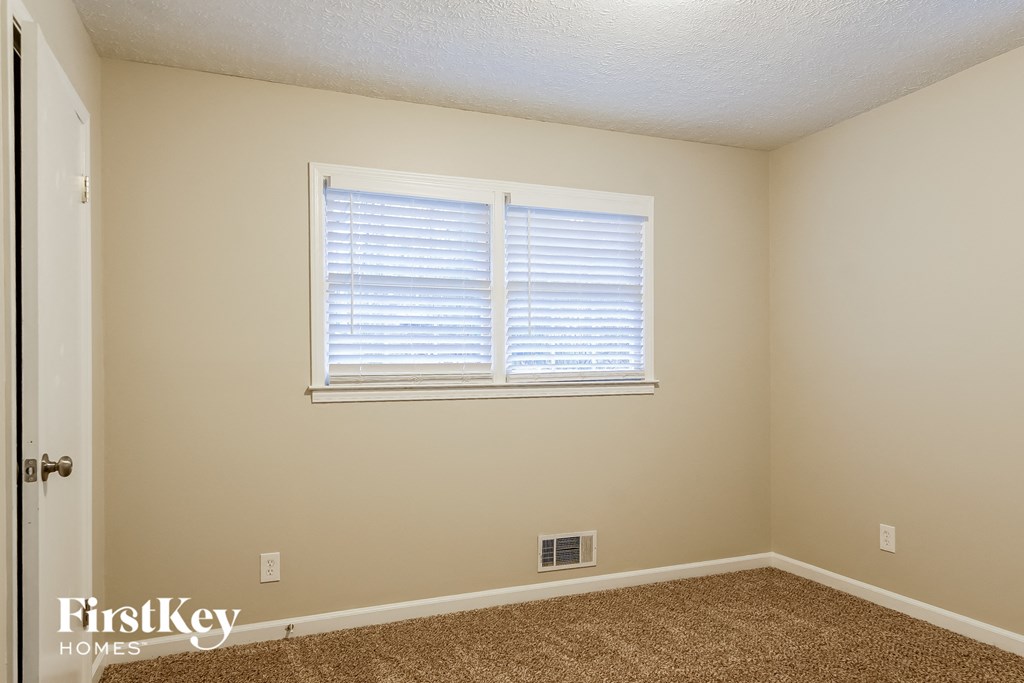 a bedroom with a window and a carpeted floor