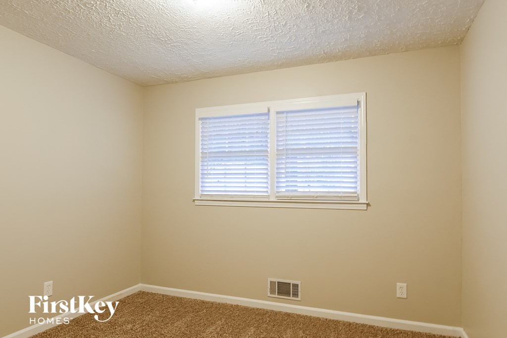 a bedroom with a window and a carpeted floor