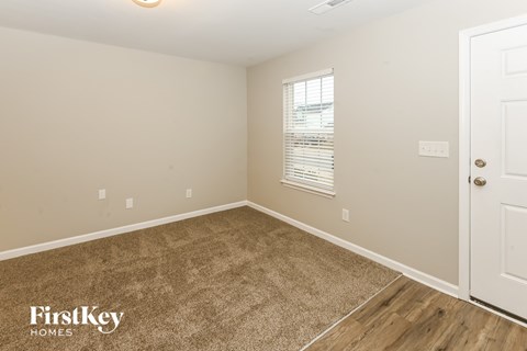 A room with a carpeted floor and a door on the right side.