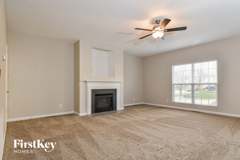 the living room with fireplace and ceiling fan