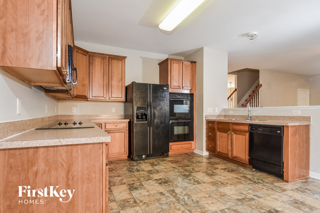 a kitchen with wooden cabinets and a black refrigerator