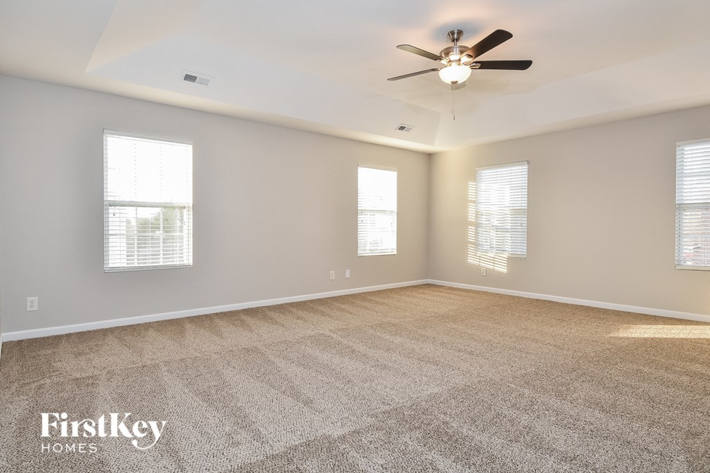 an empty living room with a ceiling fan and windows