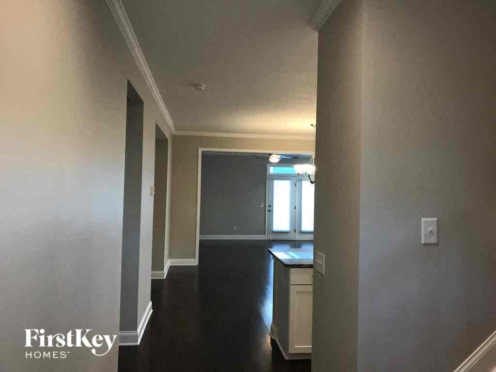 an empty hallway with a kitchen and a dark floor