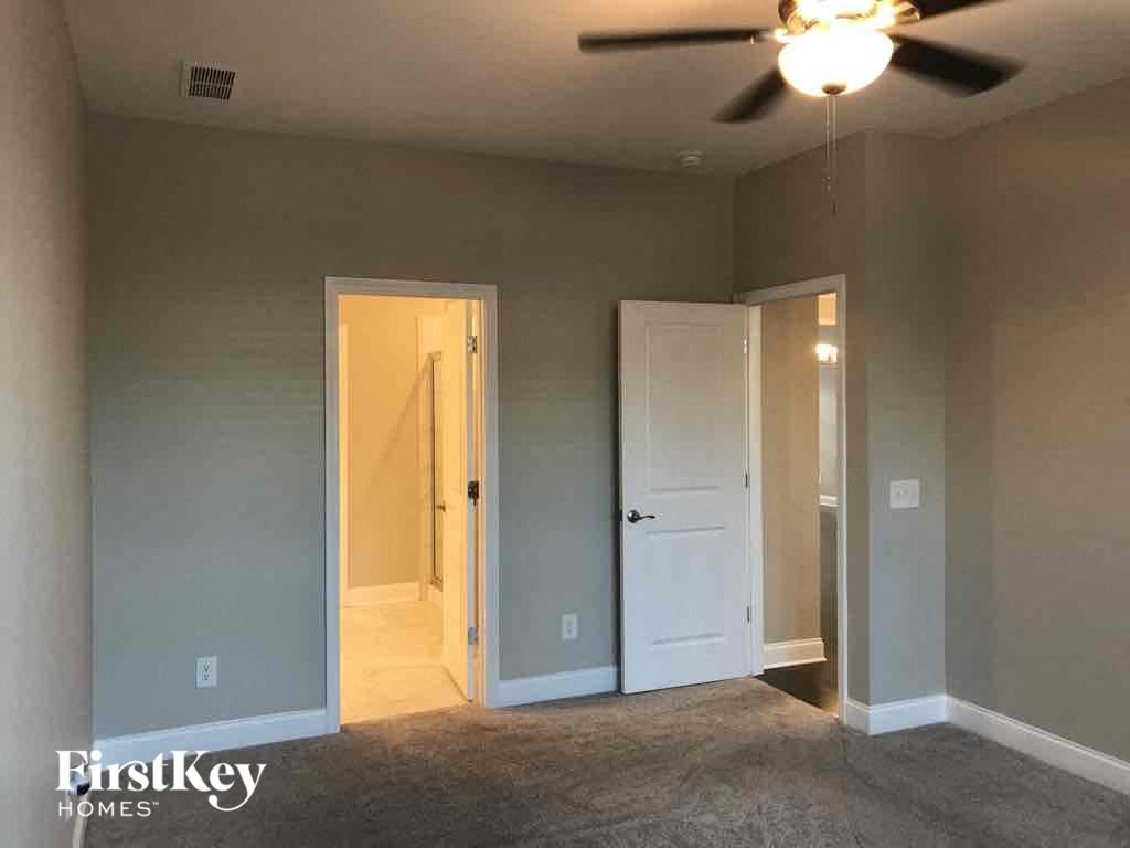 an empty living room with a ceiling fan and a door to a closet