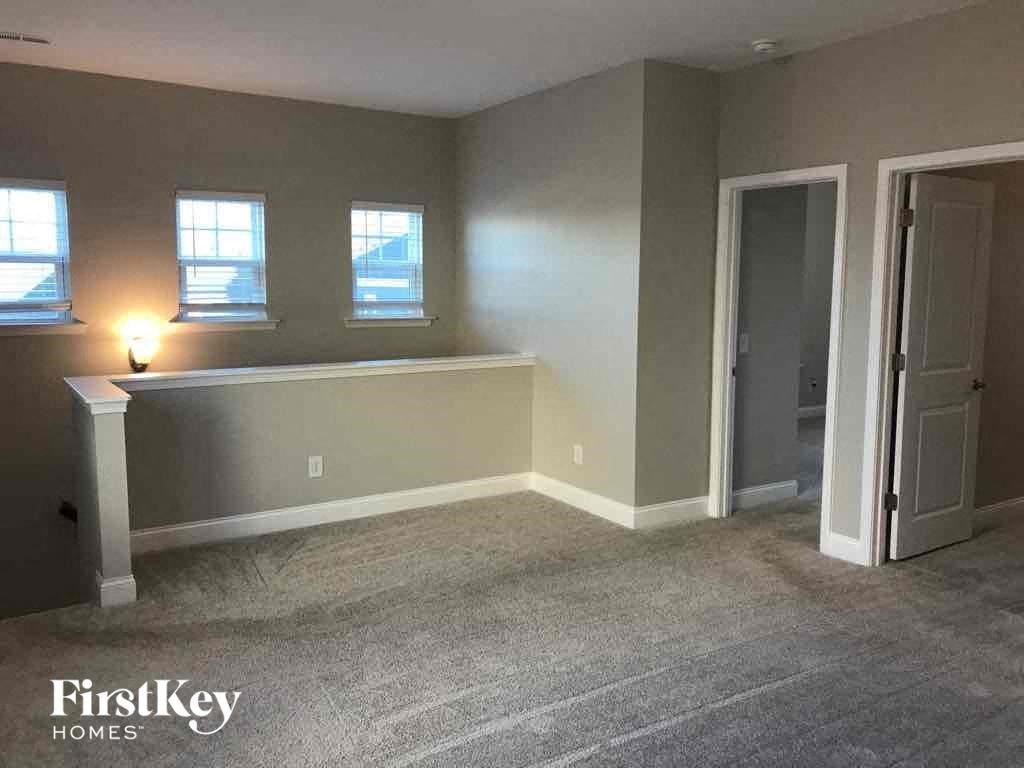 an empty living room with grey carpet and white walls